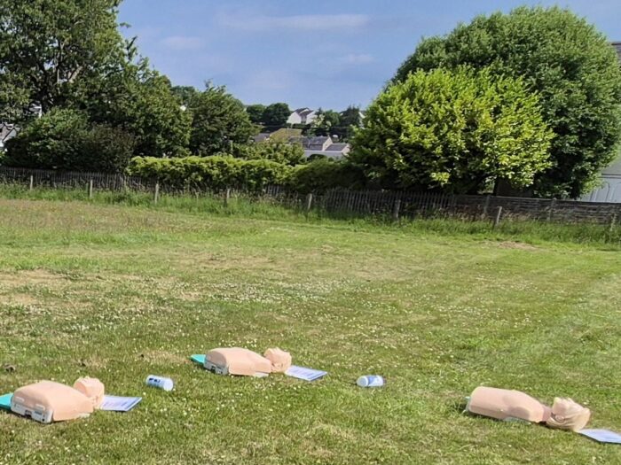 CPR training manikins laid out on grass for outdoor first aid training
